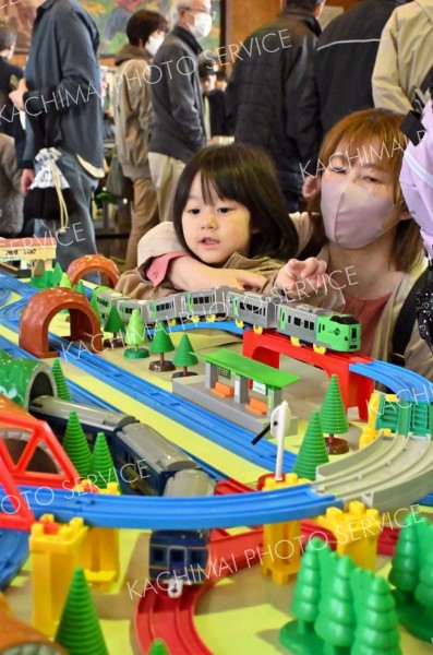 体育館の一角に子どもの目の高さで配置されたプラレールの走行展示コーナーに興味津々の母子ら