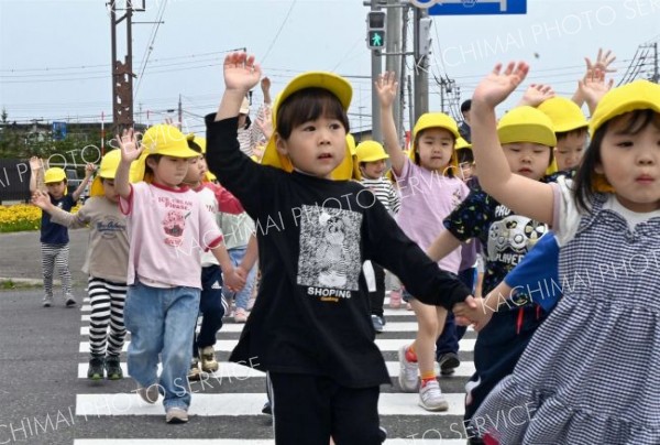 上に大きく手を上げ、ドライバーに合図を送る園児たち