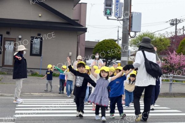上に大きく手を上げ、ドライバーに合図を送る園児たち