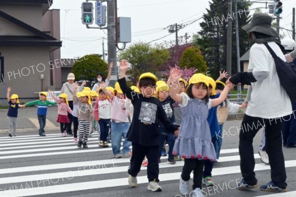 上に大きく手を上げ、ドライバーに合図を送る園児たち