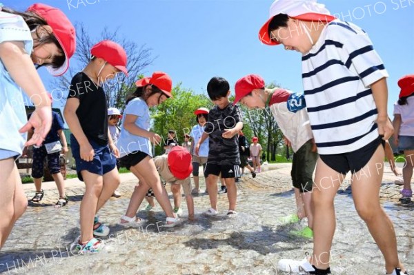 夏のような日差しの下、水遊びを楽しむ柏小の１年生（１６日午前１１時ごろ、帯広市の光南緑地公園で。須貝拓也撮影）