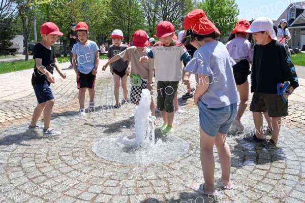 夏のような日差しの下、水遊びを楽しむ柏小の１年生（１６日午前１１時ごろ、帯広市の光南緑地公園で。須貝拓也撮影）