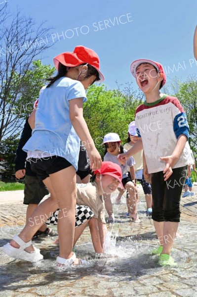 夏のような日差しの下、水遊びを楽しむ柏小の１年生（１６日午前１１時ごろ、帯広市の光南緑地公園で。須貝拓也撮影）