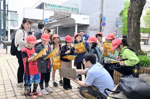 大和田学芸員（右手前）から旧藤丸の当時のにぎわいの動画を見る児童（金野和彦撮影）