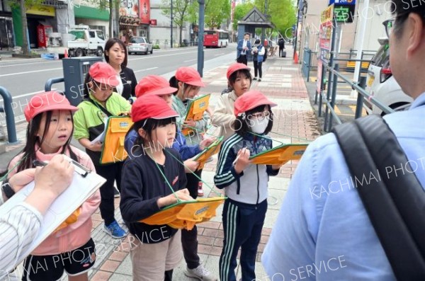 まちなかで看、板を見ながら大和田学芸員（右手前）の説明を受ける児童（金野和彦撮影）