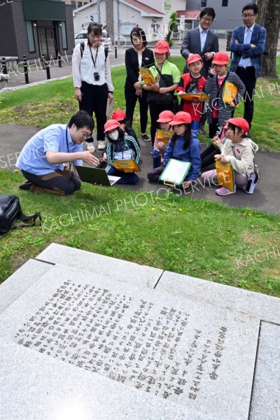 旧帯広小学校跡地（現帯広中央公園）で、大和田学芸員（左手前）の説明を受ける児童ら（金野和彦撮影）