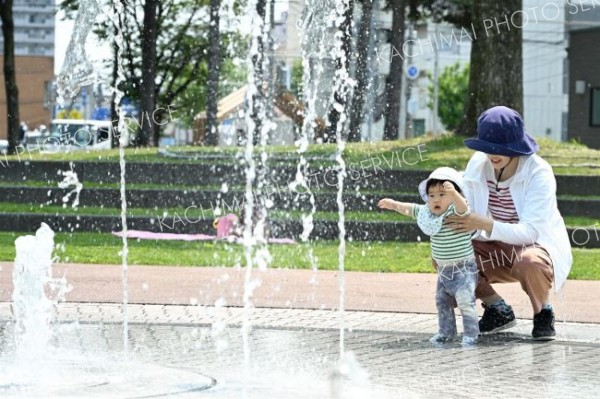 噴水で水遊びを楽しむ親子（２９日午前１０時ごろ、帯広市の中央公園で。須貝拓也撮影）