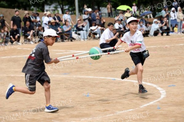 ３、４年生による競技「はさんで　はこんで」。協力しながらボールを運ぶ児童ら（７日、帯広、助川かおる通信員撮影）