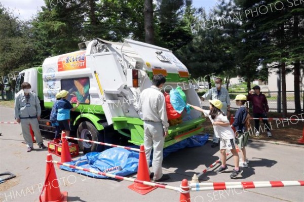 収集車へのごみの積み込み体験を行う児童たち
