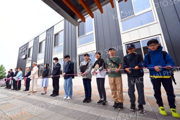 施設のオープンを祝い、テープカットを行う関係者と地元住民（１５日、午前１０時２０分ごろ。ＪＲ新得駅前で。金野和彦撮影）