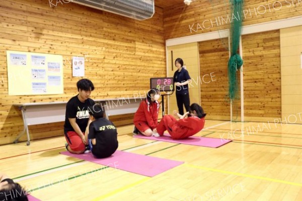 中学生に足を押さえてもらい、体力測定に臨む児童