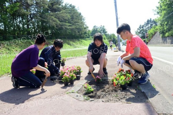 高校前の坂で花を植える生徒