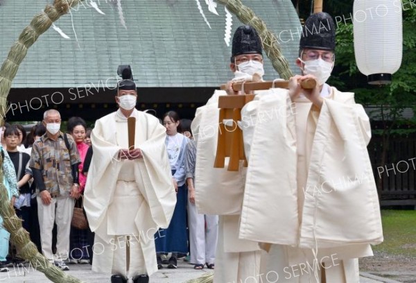 茅の輪をくぐる大野宮司（奥、塩原真撮影）