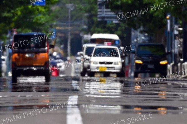 熱せられたアスファルトの上を走行する車（８日午前１１時半ごろ、市内西１南９。金野和彦撮影