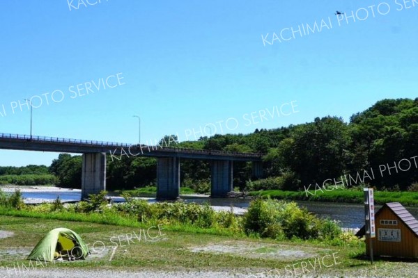 河川敷にいるクマをけん制しながらキャンパーに指示を出すドローン（右上）