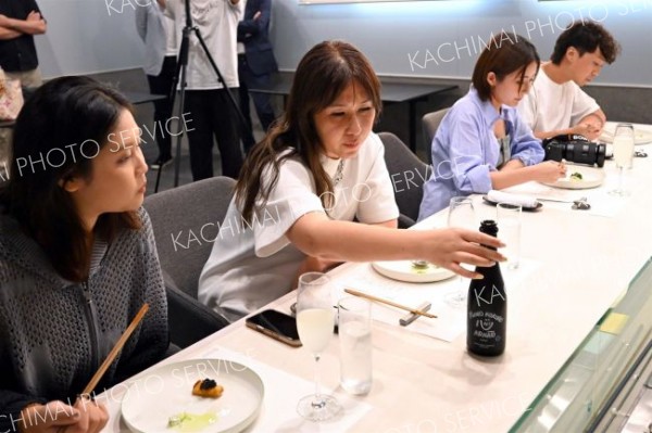 日本酒のラベルを興味深そうに見つめるモニターツアー参加者（須貝拓也撮影）