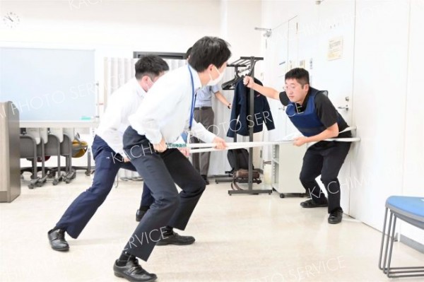 さすまたで署員が扮する不審者を壁に押しつける職員