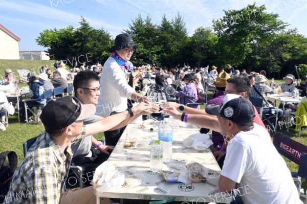 青空の下、十勝ワインで乾杯する参加者