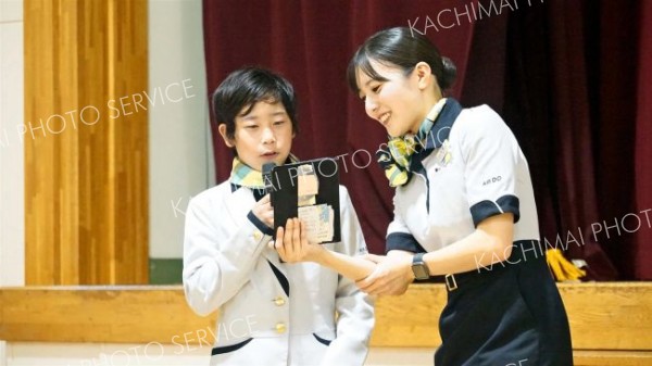 客室乗務員から機内アナウンスの指導を受ける児童