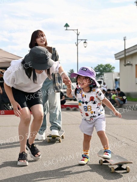 教わりながらスケートボード体験する子ども