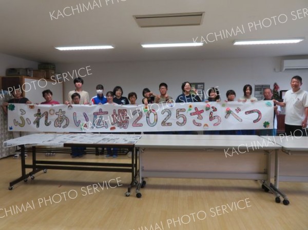 協力して完成させた横断幕を手にする高齢者と生徒たち