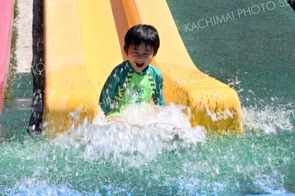 水を浴びながら滑り台を下りる子ども（２４日午前１０時１５分ごろ、芽室公園で。須貝拓也撮影）