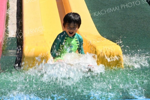 水を浴びながら滑り台を下りる子ども（２４日午前１０時１５分ごろ、芽室公園で。須貝拓也撮影）