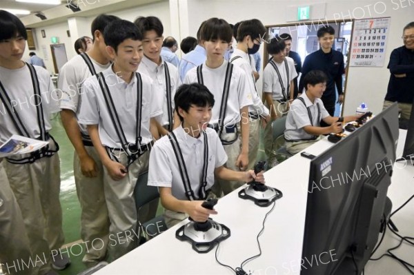 シミュレーターでバックホー操作を体験する生徒たち
