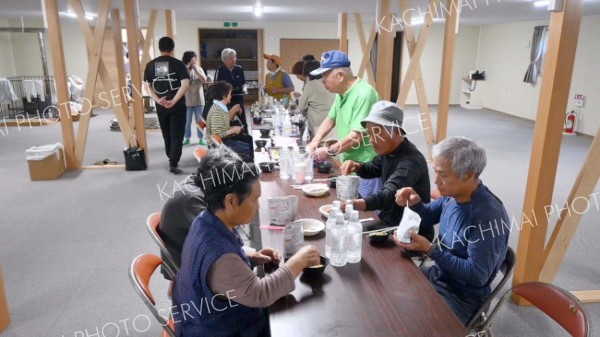 広尾町音調津の避難施設で備蓄された非常食による夕食を済ませる地域住民ら。婦人防災クラブのメンバーたちが率先して準備に当たった（７月３０日午後６時１０分ごろ）