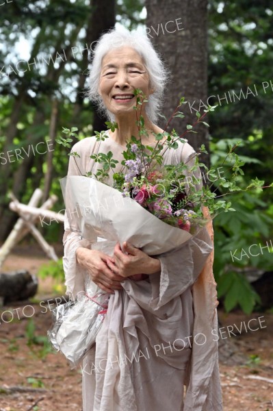 花束を手に笑顔を輝かせる
