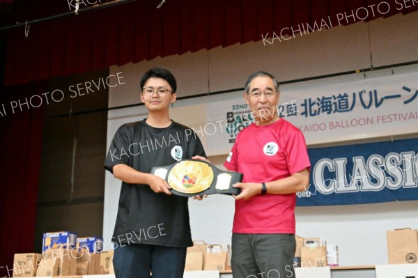 「ＢＬＳ部門」で優勝した「京都大学熱気球部Ｂ」のパイロット風張僚太さん（左）とチャンピオンベルト