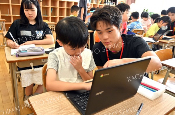帯広柏葉生（右）に勉強を教えてもらう児童（左）