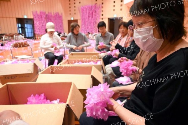 平らな形で美濃市から送られてきたこよりが付いた和紙を、花形に成形する参加者