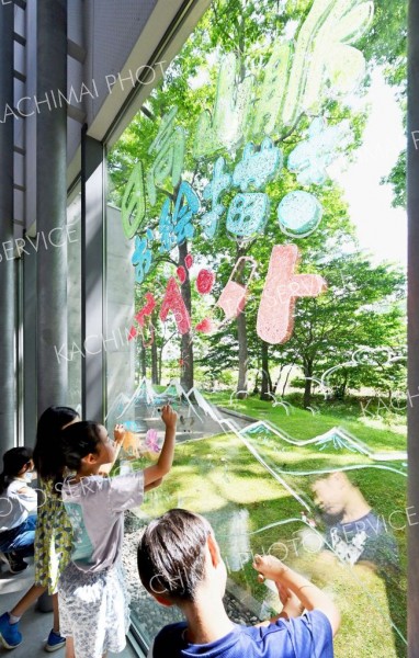 クレヨンで窓ガラスに日高山脈の動植物を描く子どもたち（１２日、塩原真撮影）