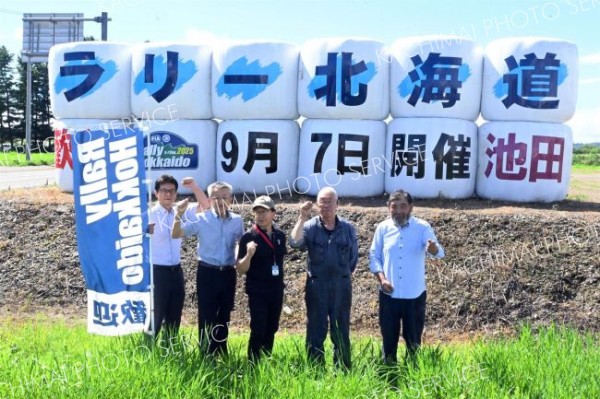 麦稈ロールで作った看板と成功させる会のメンバー