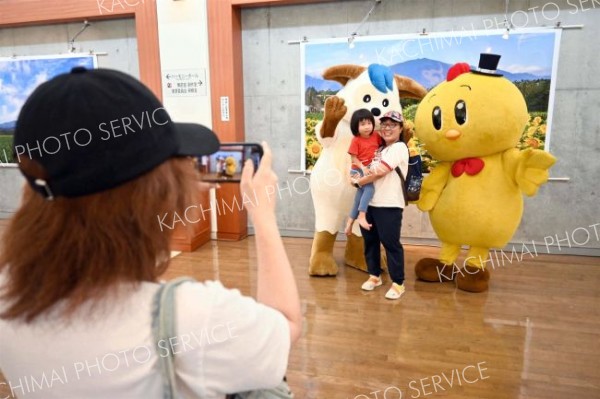 日高山脈の写真の前で記念写真を撮る来場者ら