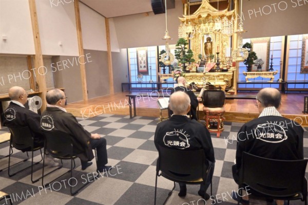 会をイメージした法被姿で物故者の法要を行うメンバー