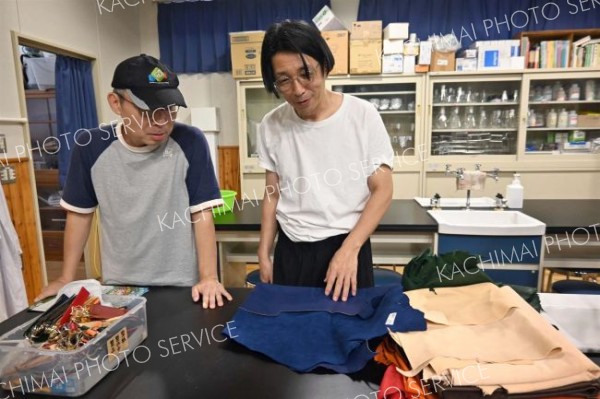 加工された一般的なピッグスキン（豚のレザー）を手に取る勝川さん（右）。左は瀬尾准教授