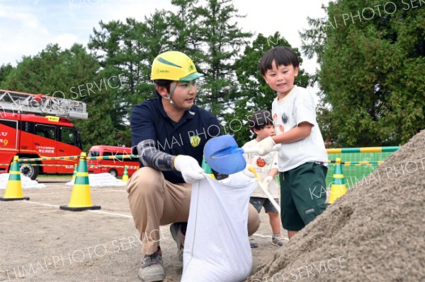 土をすくい土のう作りに挑戦する子ども