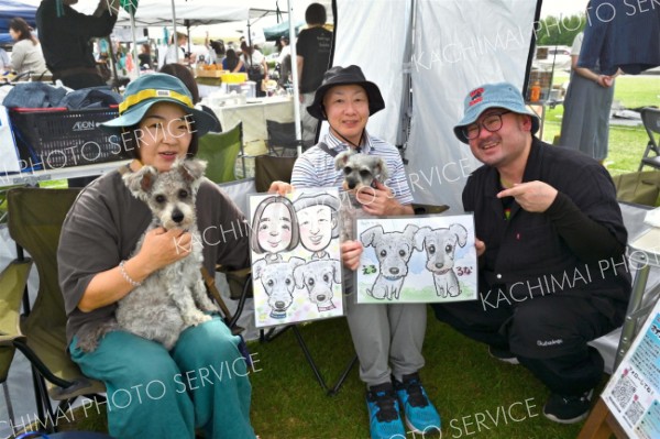 プロの似顔絵師の及川勝己さん（右、釧路管内厚岸町在住）が描いたマンガチックな似顔絵が人気を集めた。完成した作品に感激する来場者
