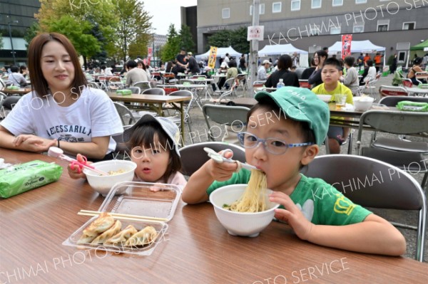 大好きなラーメンや餃子を味わう子ども（２０日午前１１時ごろ、駅北多目的広場で。金野和彦撮影）