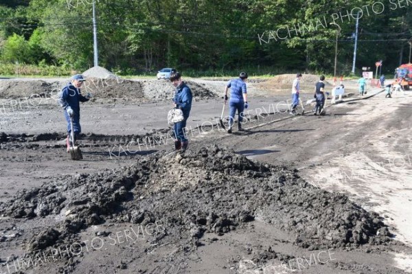 町道や歩道に溜まった汚泥をかき出す町職員