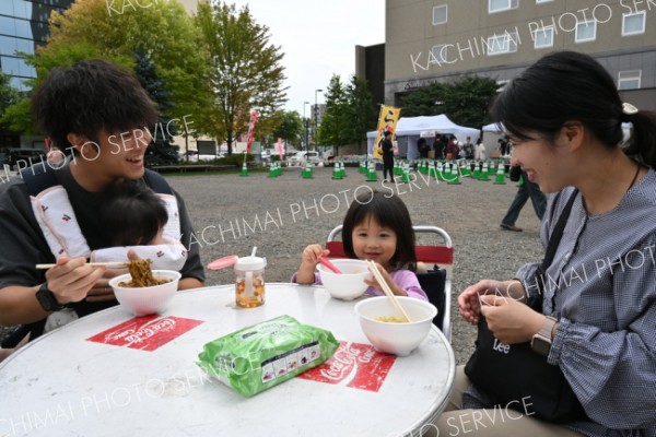 おかわりしゃちゃおうかな―。ラーメンを食べて笑顔を見せる親子連れ（２０日、「十勝ラーメンフェスタ２０２５」駅北多目的広場で。金野和彦撮影）