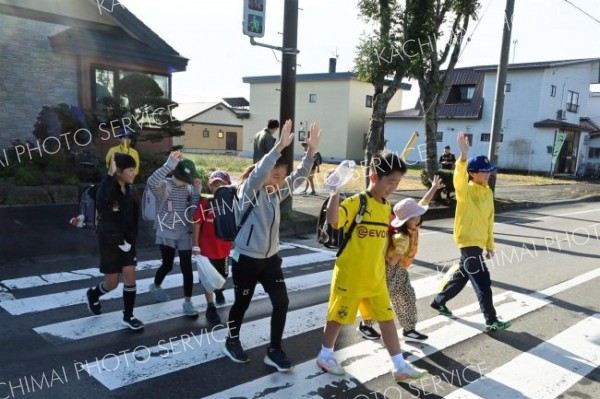 安全確認して歩行者と一緒に横断歩道を渡る団員（右端）