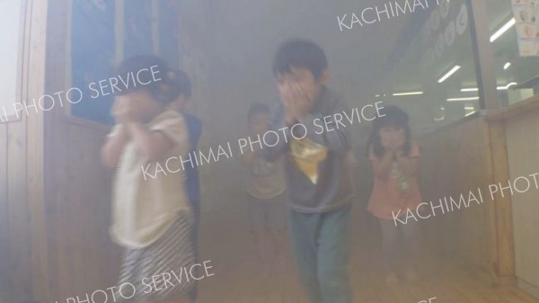 煙の中を避難誘導体験する園児