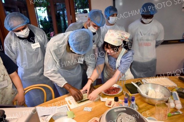 協力しながら巻きずしを作る生徒と研修員。完成すると拍手が起こった。