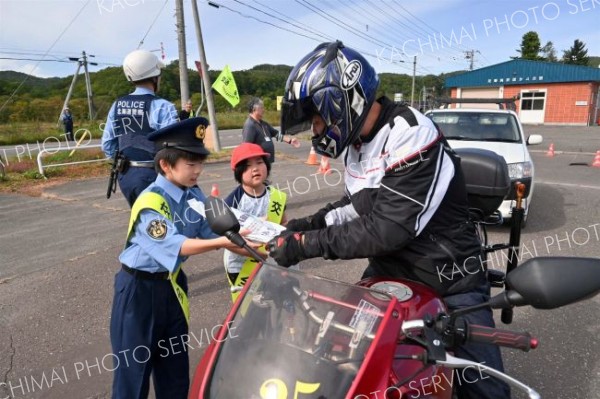 国道２４２号を通行するライダーに安全運転を呼びかける大誉地小の児童
