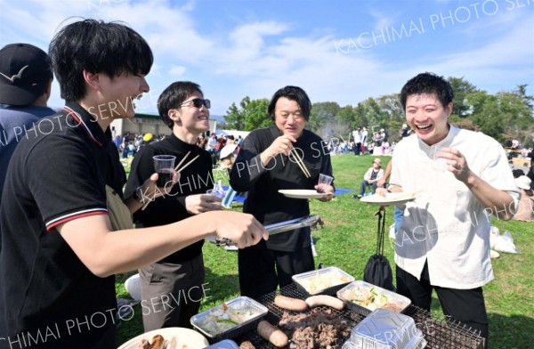 秋晴れの下、ワインを片手に食事を楽しむ来場客（５日午前１０時５０分ごろ、池田・ワイン城横イベント広場。塩原真撮影）