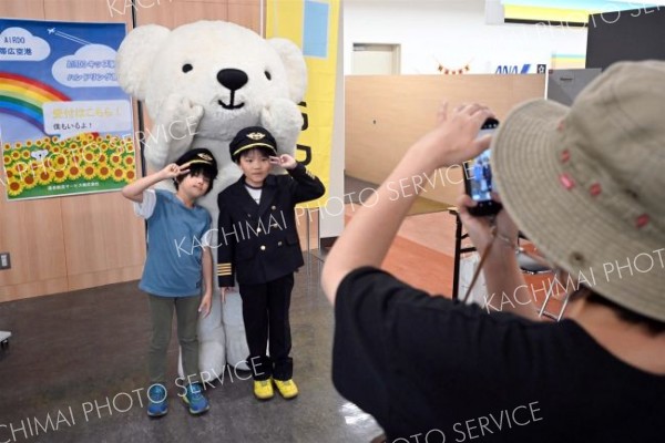 パイロットの制服を着てマスコットと記念撮影する子ども（須貝拓也撮影）