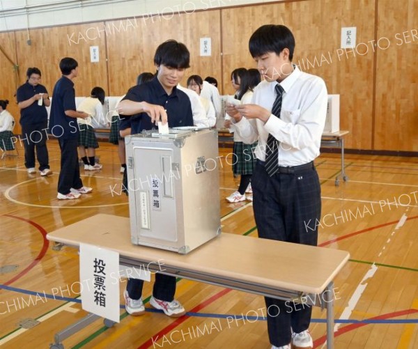 体育館に設置された投票箱に一票を投じる生徒